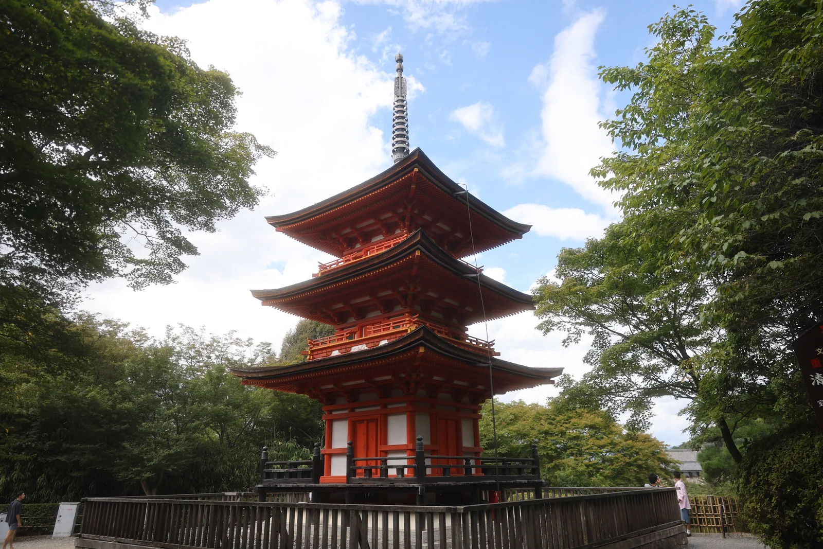 A red pagoda rising above the treeline against a blue sky.